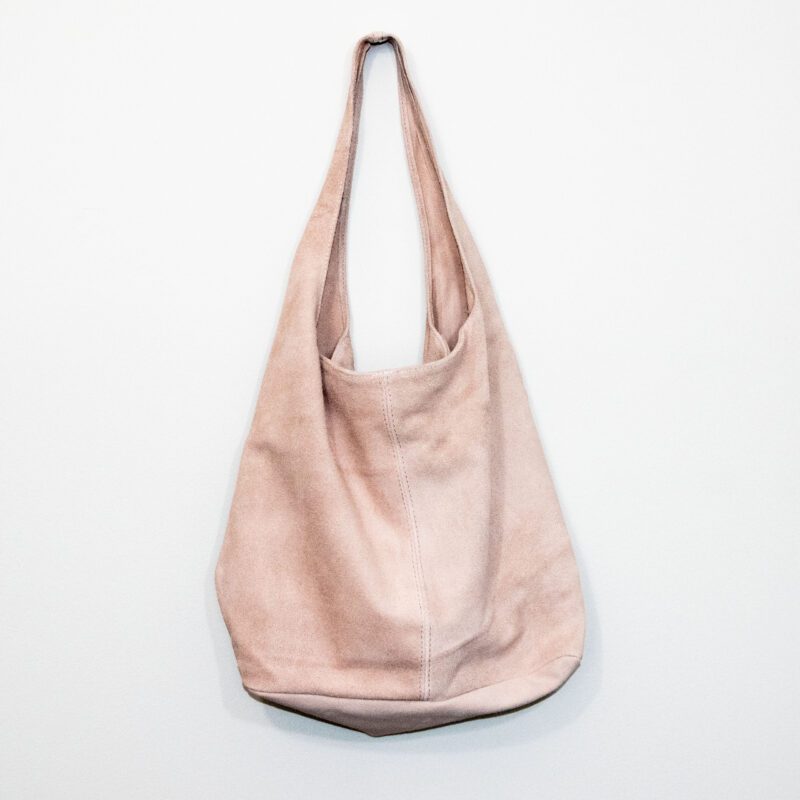 Powder pink colored suede leather hobo bag on white background